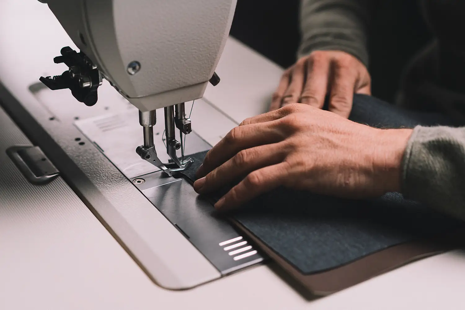 Hände beim Nähen mit einer weißen Nähmaschine