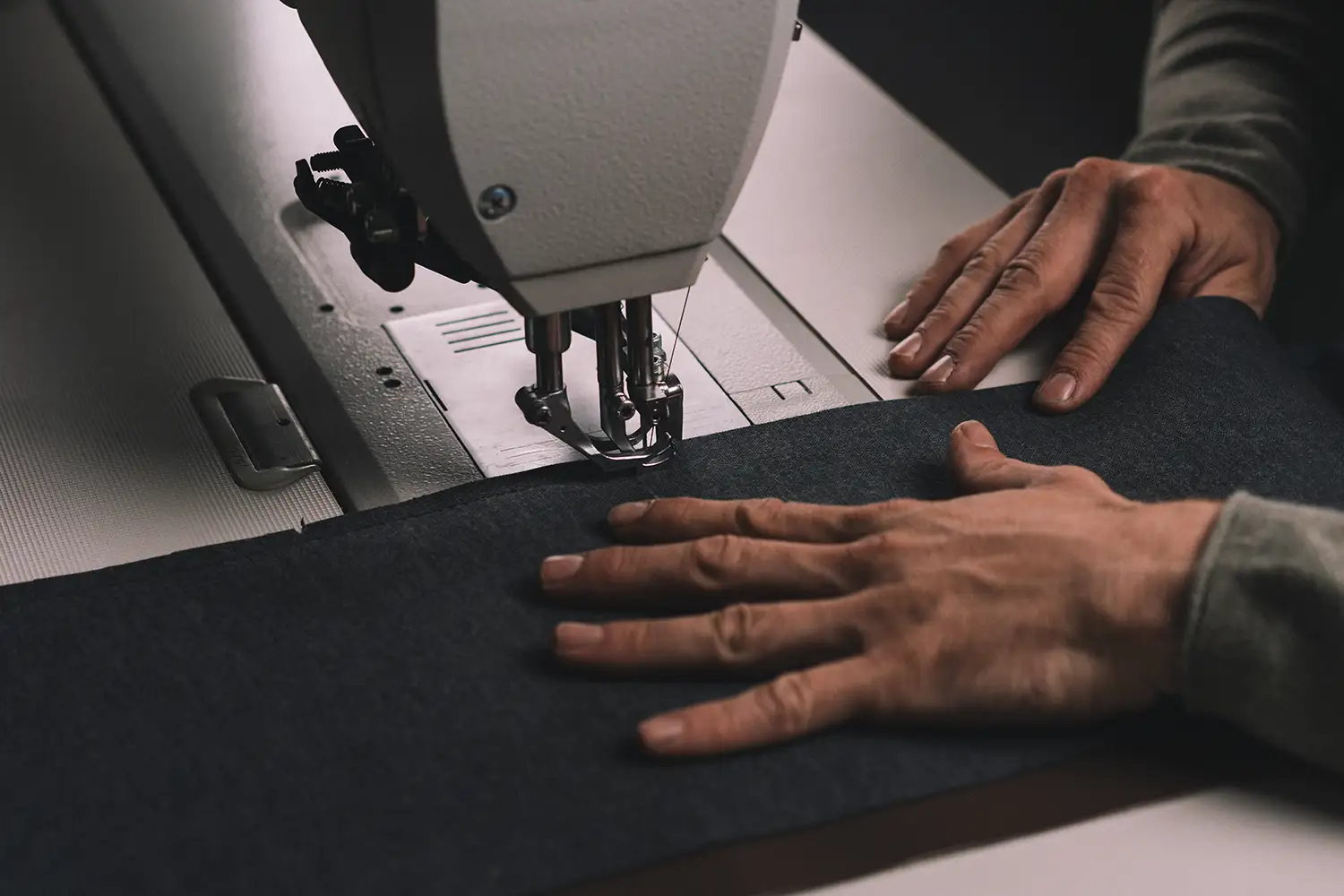 Hände beim Nähen von Stoff mit einer Nähmaschine